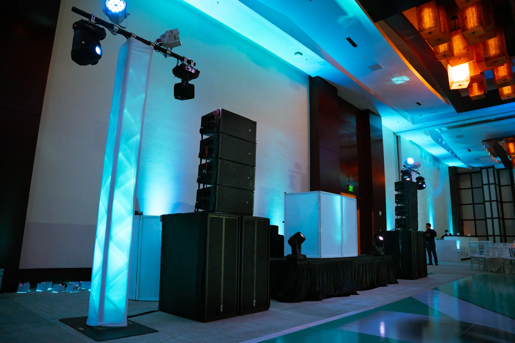Event speakers, lighting and a white DJ booth in a ballroom