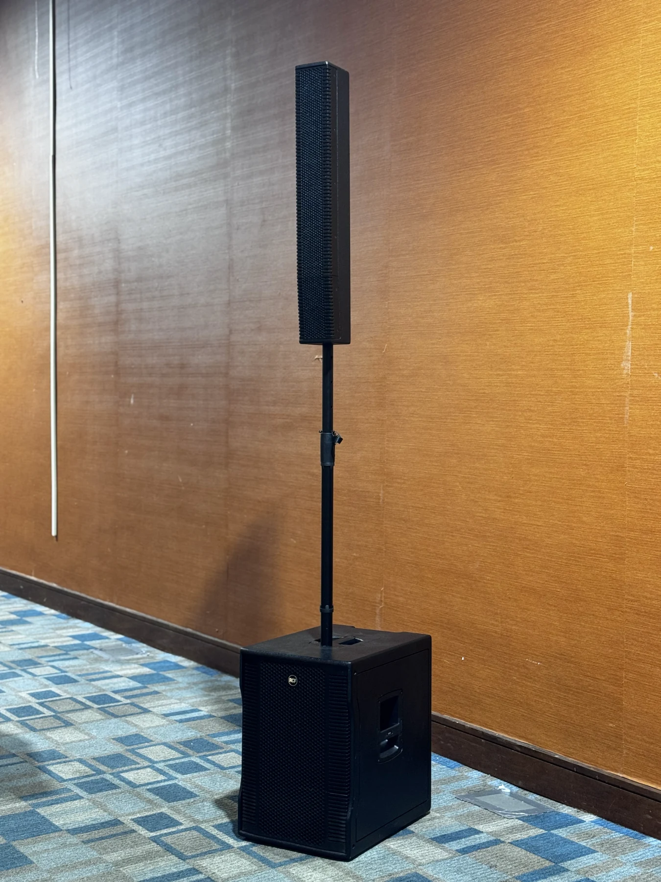 A column loudspeaker and subwoofer set beside a ballroom wall