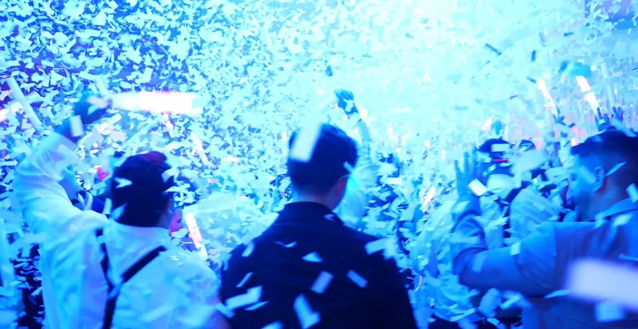Guests beneath a burst of white confetti and blue lighting