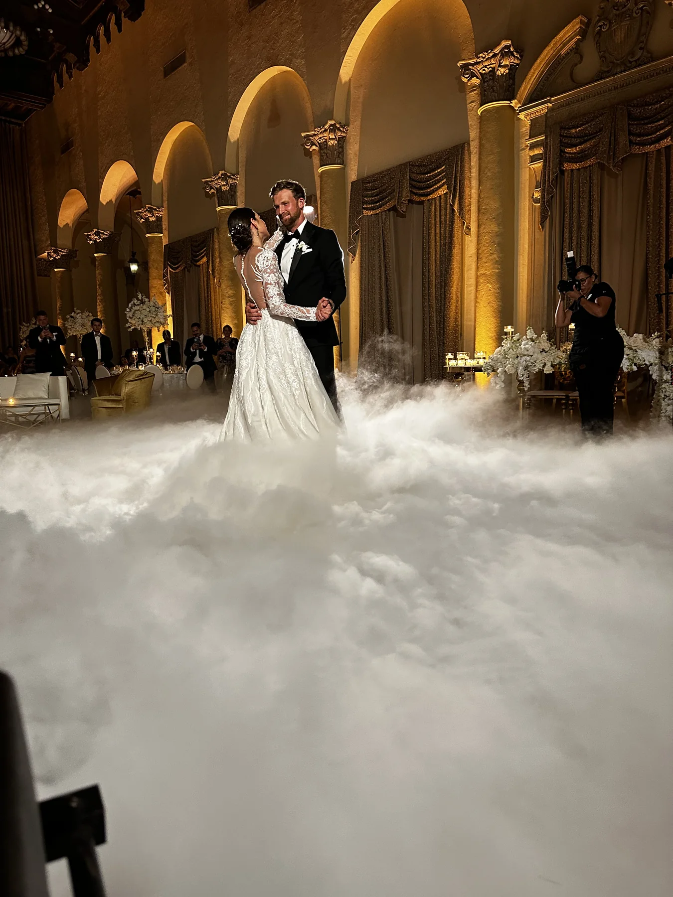 A couple dancing above low-lying fog in a warmly lit ballroom