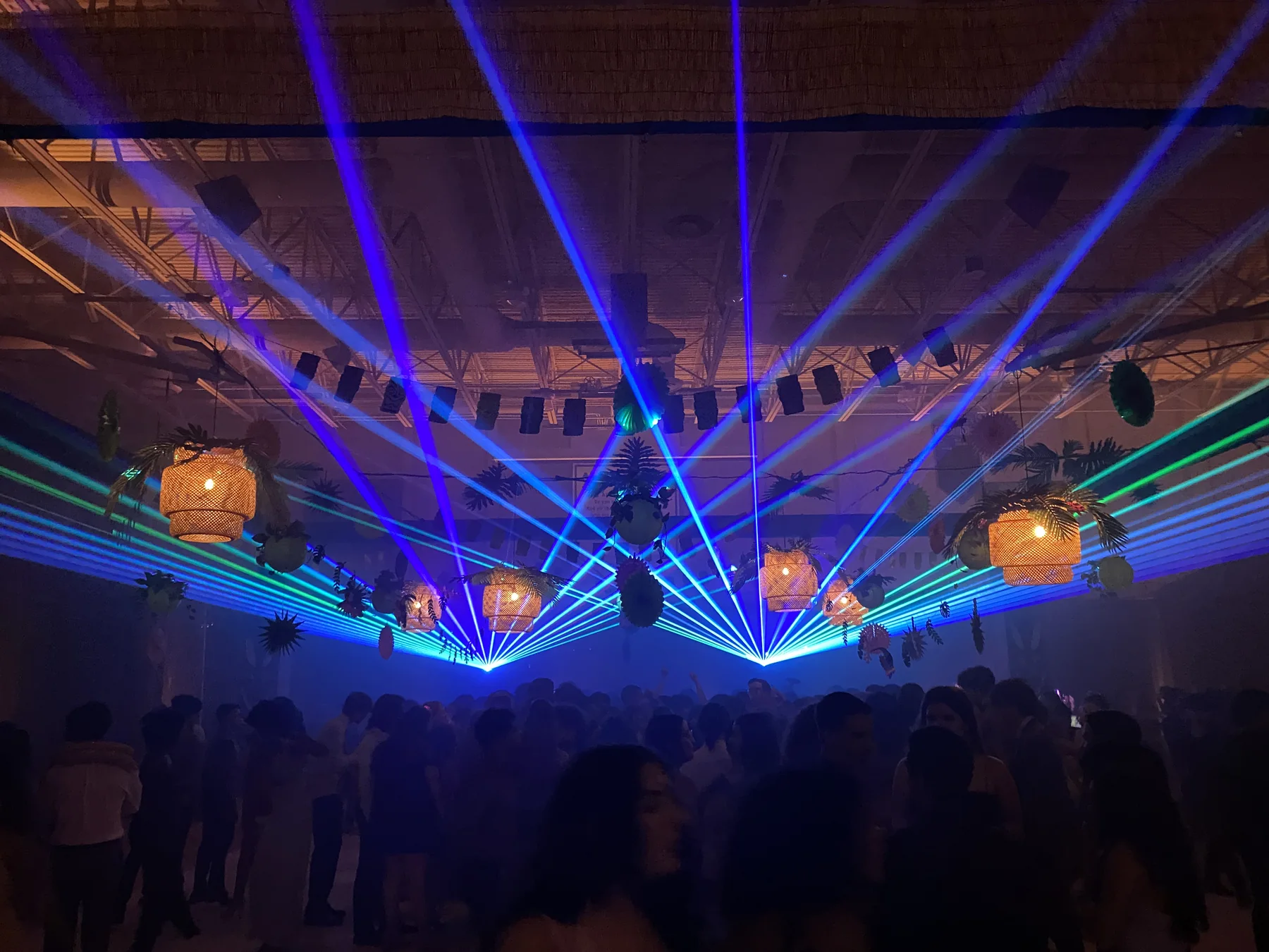 Blue and green laser beams above an event crowd
