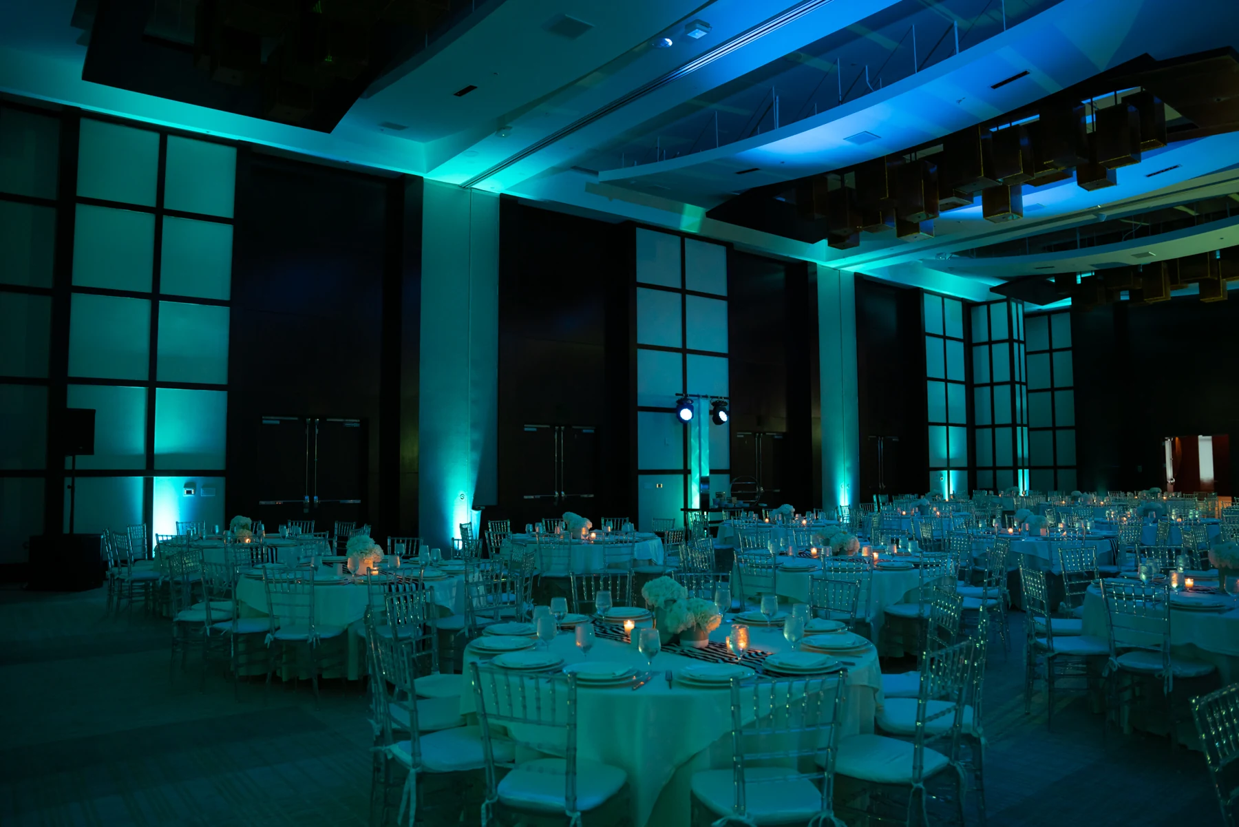 Blue uplighting and beams across a prepared event room